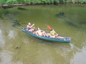 Family paddling a canoe along the calm waters of the Au Train River.