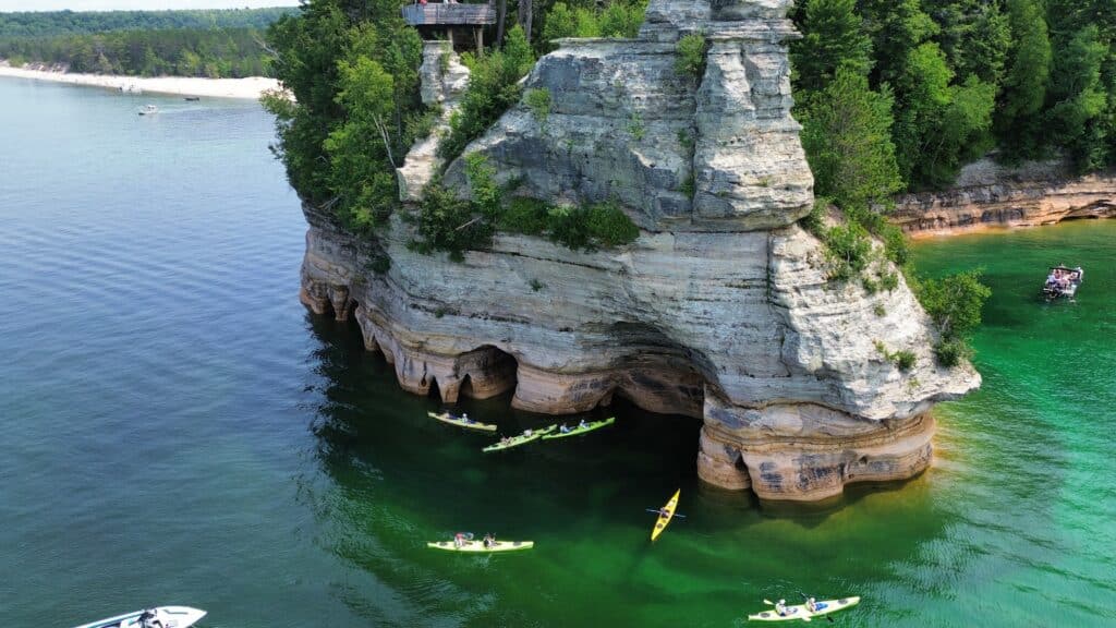 Aerial view of kayakers exploring the sea caves and sandstone cliffs at Miners Castle along Pictured Rocks National Lakeshore in Michigan’s Upper Peninsula