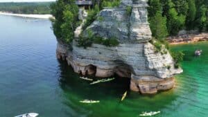 Aerial view of kayakers exploring the sea caves and sandstone cliffs at Miners Castle along Pictured Rocks National Lakeshore in Michigan’s Upper Peninsula